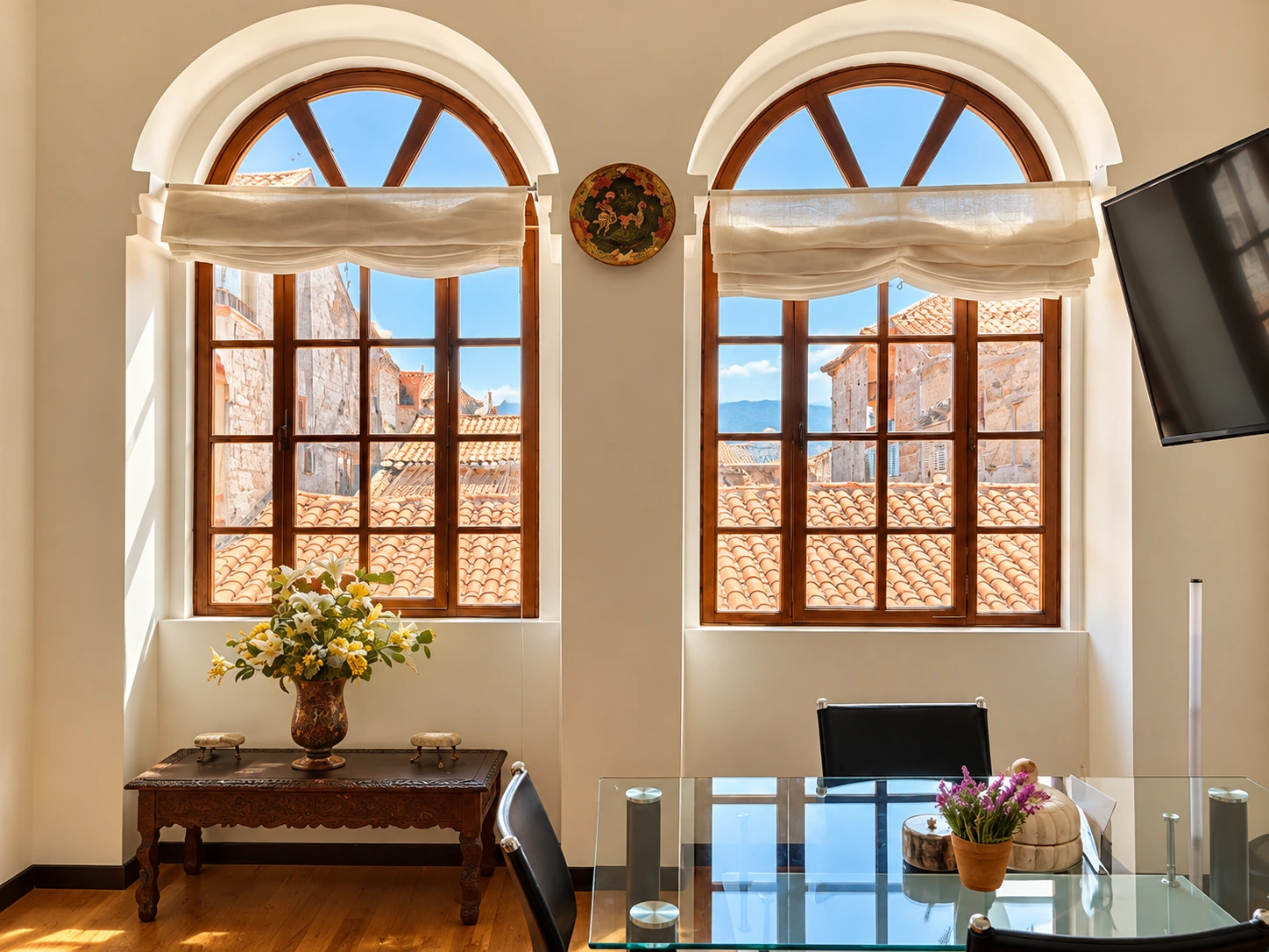 Dos grandes ventanas arqueadas de madera en Casa Sucre, con tejados tradicionales de Cuenca al fondo